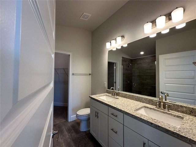 bathroom featuring wood-type flooring, vaulted ceiling, toilet, vanity, and a shower with shower door