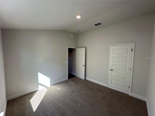 unfurnished bedroom with dark colored carpet, a closet, and vaulted ceiling