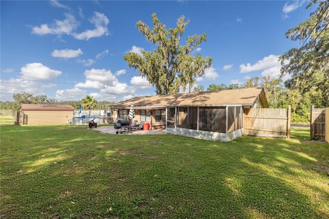 back of property with a patio, a lawn, a sunroom, and a storage shed