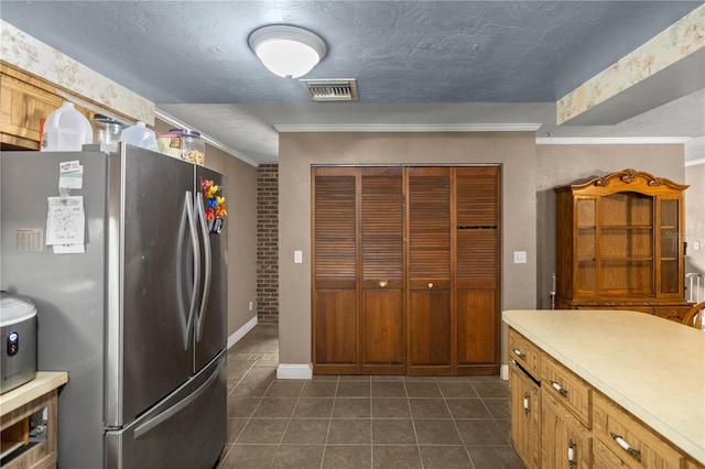 kitchen featuring stainless steel fridge, a textured ceiling, dark tile patterned flooring, and ornamental molding