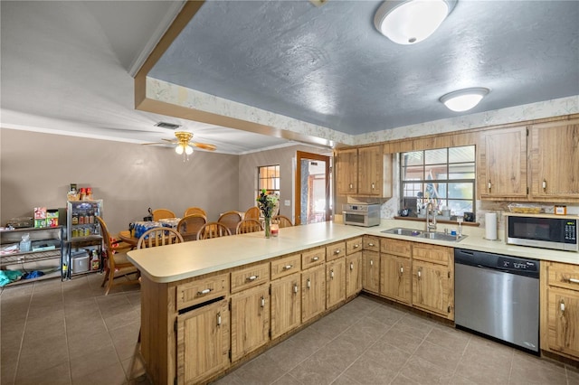 kitchen featuring kitchen peninsula, sink, ornamental molding, ceiling fan, and appliances with stainless steel finishes