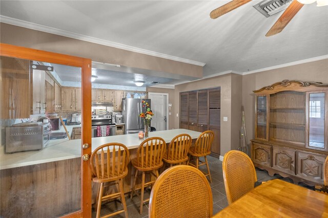 tiled dining area with ceiling fan and crown molding