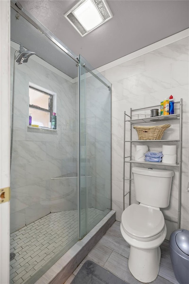 bathroom with walk in shower, tile walls, tile patterned floors, and toilet