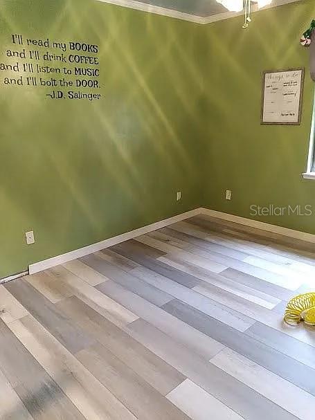 empty room with hardwood / wood-style floors and ornamental molding