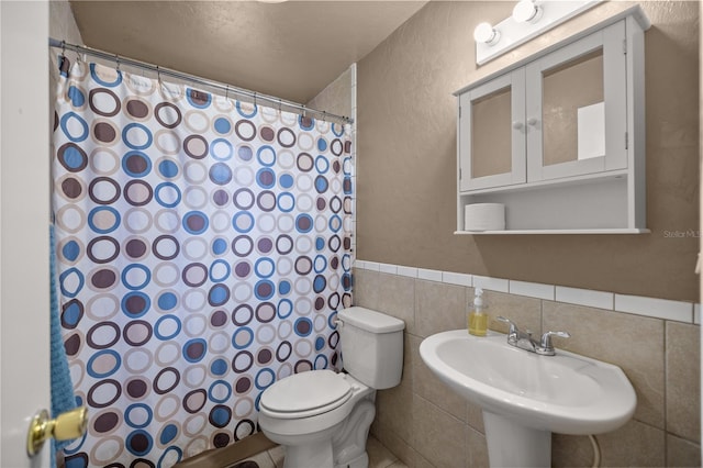 bathroom featuring tile walls, walk in shower, a textured ceiling, sink, and toilet