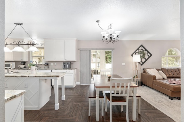 dining space featuring a notable chandelier, dark parquet flooring, and plenty of natural light