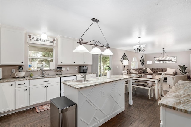 kitchen with sink, white cabinetry, decorative light fixtures, and a center island