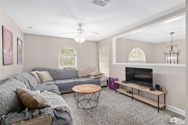 carpeted living room featuring ceiling fan with notable chandelier and a textured ceiling