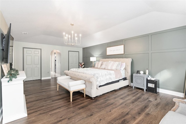 bedroom featuring dark hardwood / wood-style flooring, lofted ceiling, and a notable chandelier