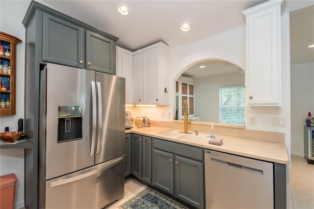 kitchen featuring white cabinets, sink, gray cabinets, light tile patterned floors, and stainless steel appliances