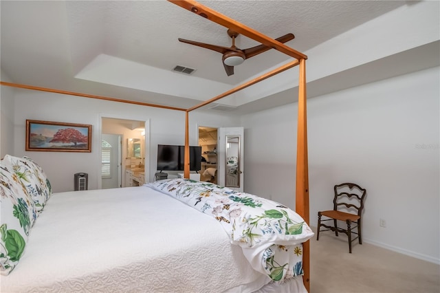 bedroom featuring connected bathroom, ceiling fan, light colored carpet, and a textured ceiling