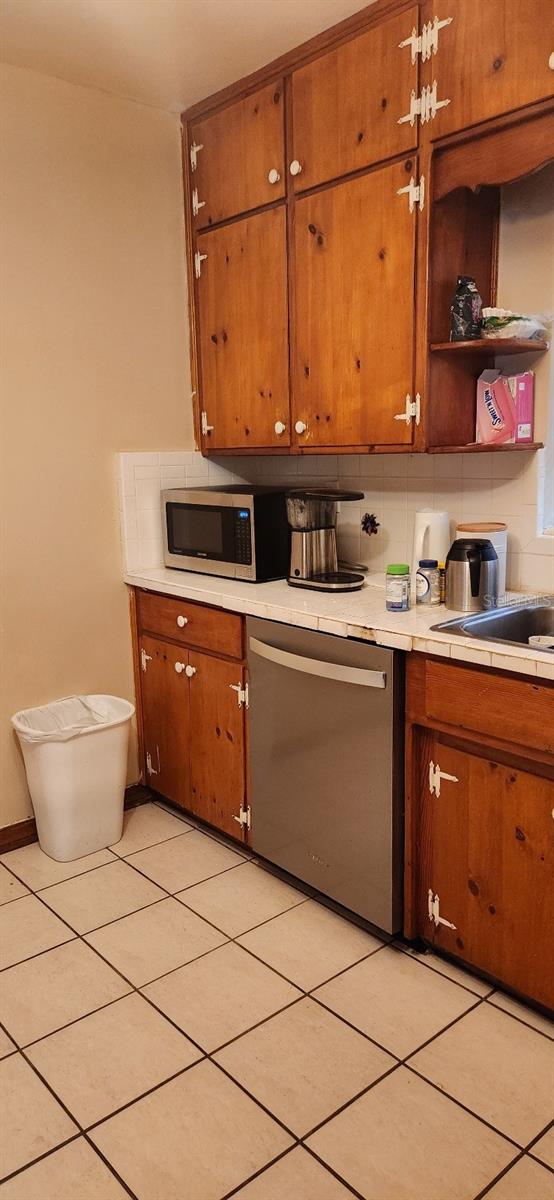 kitchen featuring appliances with stainless steel finishes, light tile patterned floors, tasteful backsplash, and sink