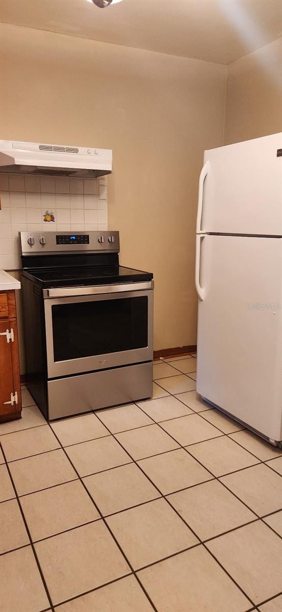 kitchen featuring tasteful backsplash, white fridge, extractor fan, light tile patterned floors, and stainless steel electric range oven