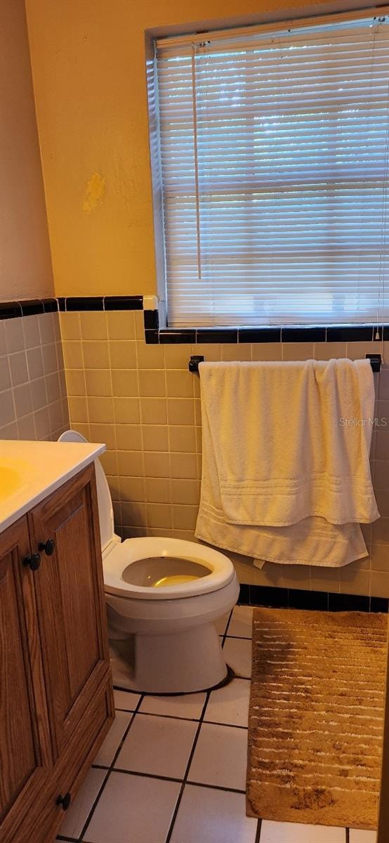 bathroom featuring toilet, tile walls, vanity, and tile patterned floors