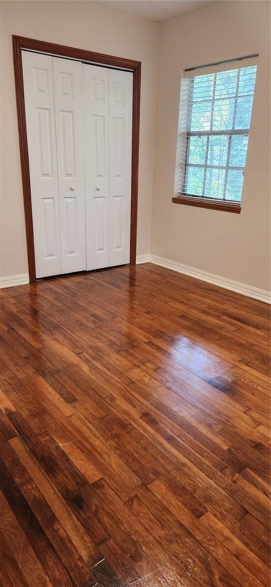 unfurnished bedroom with a closet and dark hardwood / wood-style flooring