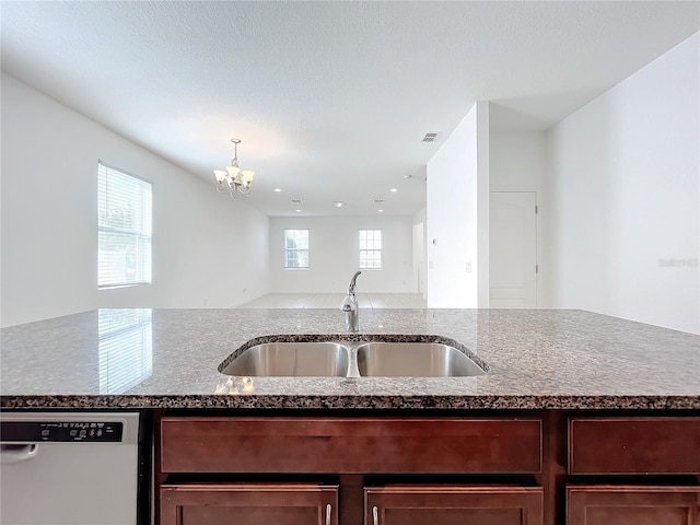 kitchen featuring a chandelier, sink, stainless steel dishwasher, and light stone counters