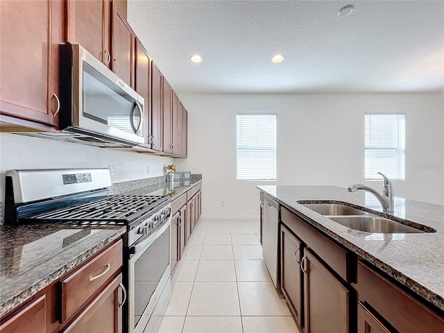 kitchen with stainless steel appliances, plenty of natural light, dark stone countertops, and sink