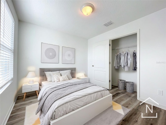 bedroom featuring a closet, wood-type flooring, and a textured ceiling