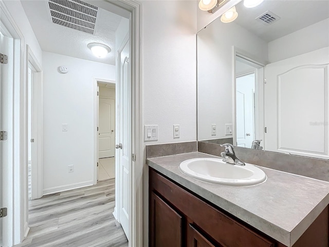 bathroom featuring wood-type flooring, vanity, and a textured ceiling