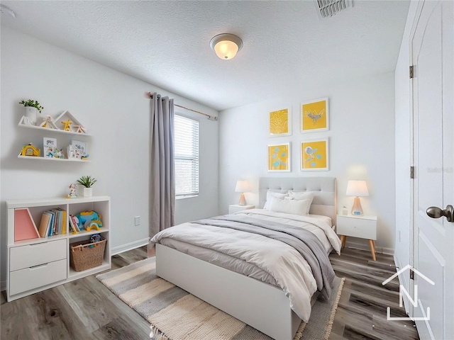 bedroom with a textured ceiling and dark wood-type flooring