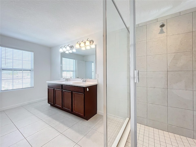 bathroom with tile patterned flooring, vanity, an enclosed shower, and a textured ceiling