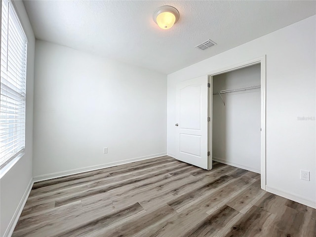 unfurnished bedroom featuring wood-type flooring, a textured ceiling, and a closet