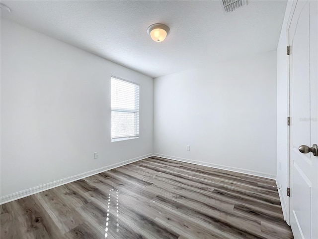 spare room featuring a textured ceiling and hardwood / wood-style flooring