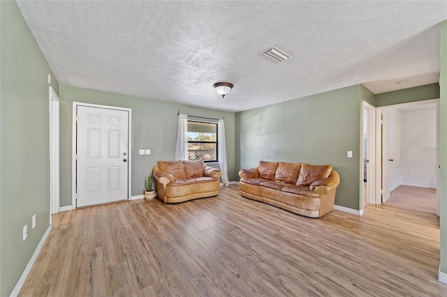 living room with visible vents, baseboards, and light wood-style floors