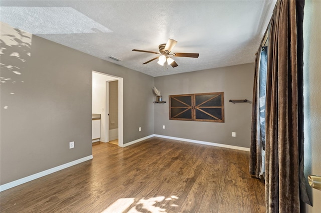 empty room with visible vents, a textured ceiling, wood finished floors, and a ceiling fan