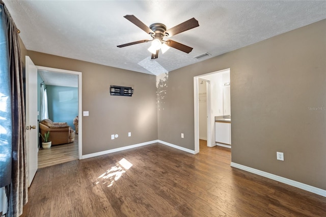 unfurnished bedroom featuring visible vents, baseboards, a textured ceiling, and wood finished floors