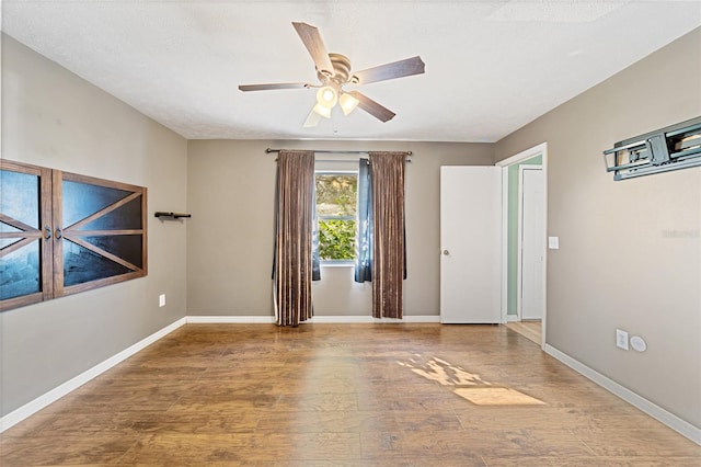 spare room with a ceiling fan, baseboards, and wood finished floors