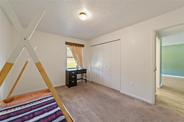 unfurnished bedroom featuring a closet, baseboards, carpet, and a textured ceiling