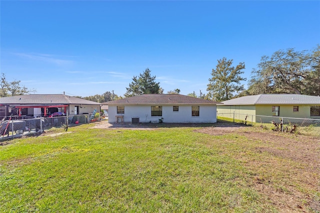 rear view of property with central air condition unit, a lawn, a fenced backyard, and stucco siding