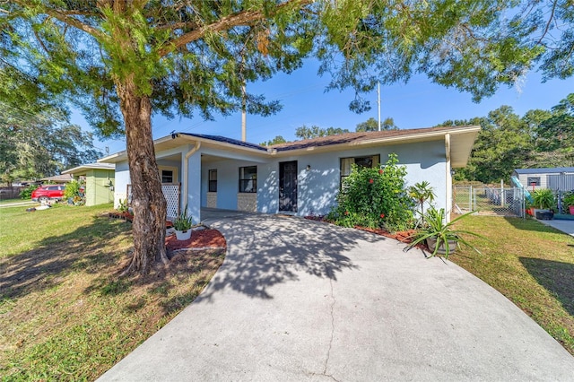 ranch-style house with an attached carport, fence, concrete driveway, a front yard, and stucco siding