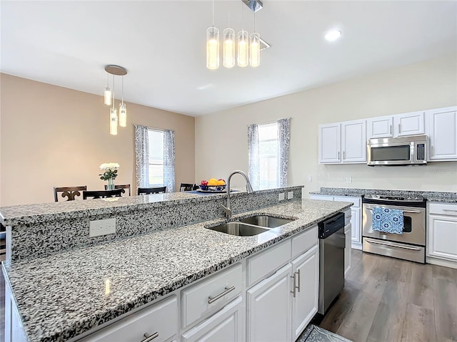 kitchen with stainless steel appliances, white cabinets, sink, and a kitchen island with sink