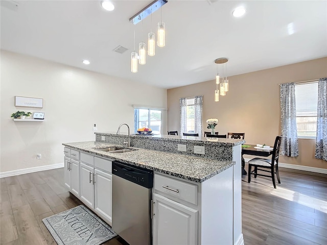 kitchen featuring stainless steel dishwasher, hanging light fixtures, a kitchen island with sink, white cabinetry, and sink