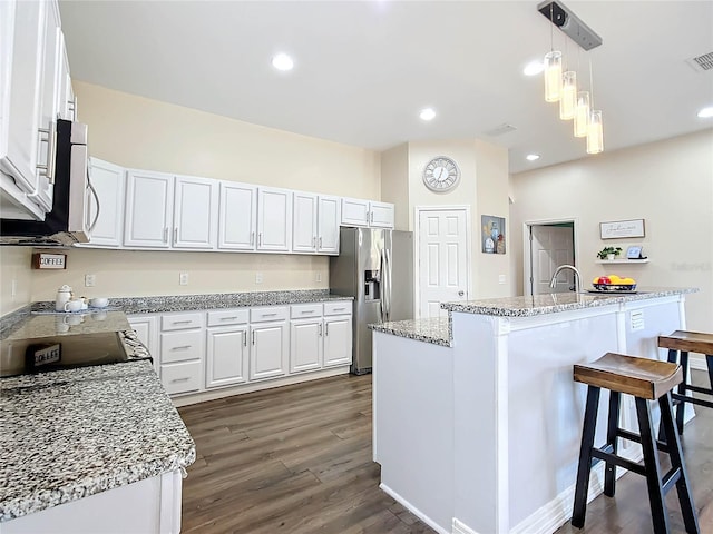 kitchen featuring decorative light fixtures, an island with sink, stainless steel appliances, dark hardwood / wood-style flooring, and white cabinetry