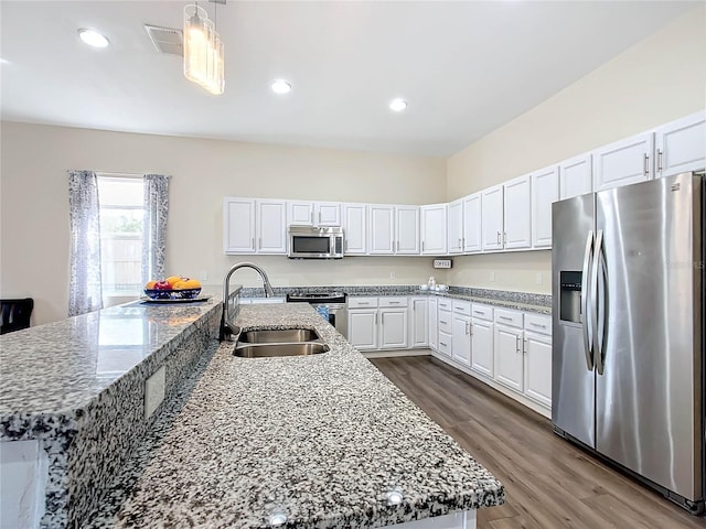 kitchen with appliances with stainless steel finishes, white cabinets, sink, and a spacious island