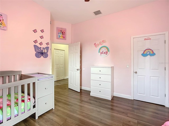 bedroom with a crib and dark hardwood / wood-style floors