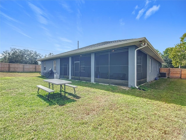 rear view of house featuring a lawn and a sunroom