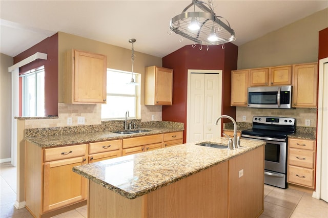 kitchen with a center island with sink, appliances with stainless steel finishes, lofted ceiling, and sink