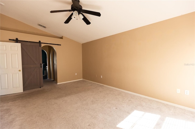 interior space with a barn door, ceiling fan, lofted ceiling, and carpet floors