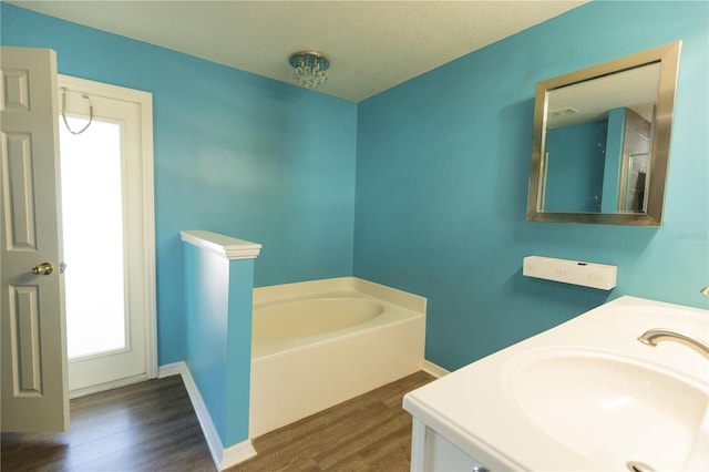 bathroom with a bathing tub, a textured ceiling, vanity, and hardwood / wood-style flooring