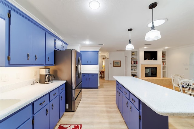 kitchen with blue cabinets, hanging light fixtures, ornamental molding, and light hardwood / wood-style flooring