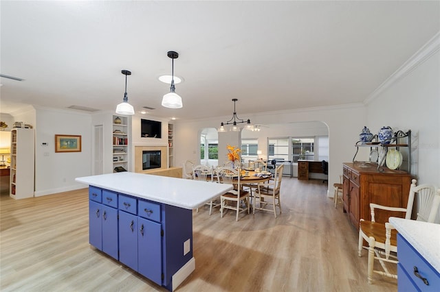 kitchen featuring ornamental molding, decorative light fixtures, blue cabinetry, light hardwood / wood-style flooring, and a center island