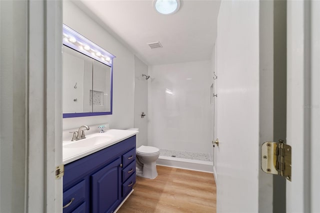 bathroom with hardwood / wood-style floors, vanity, toilet, and a shower