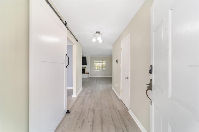 hallway with a barn door and light hardwood / wood-style floors