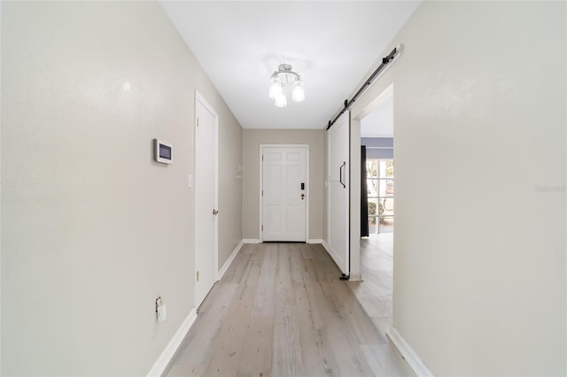 hallway with a barn door and light hardwood / wood-style floors