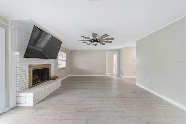 unfurnished living room with a fireplace, ceiling fan, light wood-type flooring, and ornamental molding