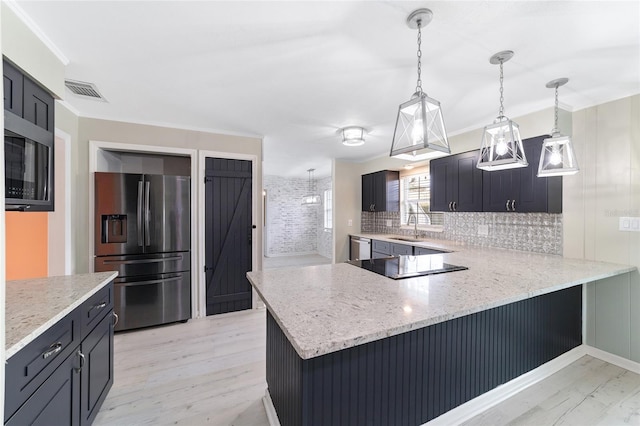 kitchen featuring light wood-type flooring, appliances with stainless steel finishes, pendant lighting, sink, and kitchen peninsula